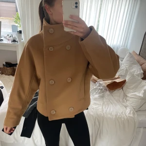 Beige kappa från Stockholm Atelier & Other Stories - Säljer en superfin beige kappa från Stockholm Atelier & Other Stories. Den har en dubbelknäppt design med stora knappar och en hög krage. Perfekt för höst och vår! 🧥Köparen står för frakten. 