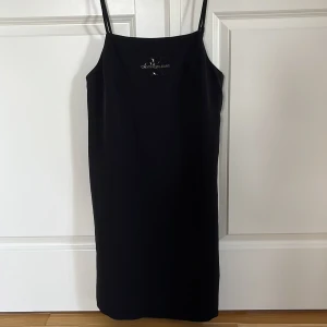 Svart klänning från Calvin Klein Jeans - Snygg svart klänning från Calvin Klein Jeans i nytt skick med prislappen kvar. Den är ärmlös med smala axelband som går att justera och har en stilren design med logotypen framtill. Perfekt för både vardag och fest ✨