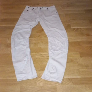 Vita byxor från G-Star - Säljer ett par vita byxor från G-Star i bra skick. De har en klassisk design med knappar och en snygg logga på baksidan. Perfekta för både vardag och fest! 🕺