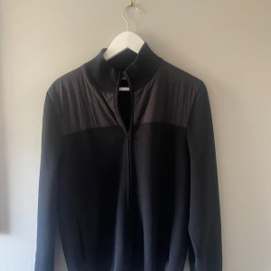 Svart tröja med dragkedja från J.Lindeberg - Säljer en stilren svart tröja/cardigan från J.Lindeberg i storlek M. Perfekt för både vardag och lite finare tillfällen. Den är i mycket bra skick och redo för en ny ägare!