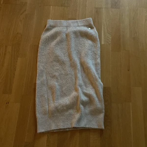 Grå ribbad kjol - Säljer en superfin grå ribbad kjol. Kjolen är i en längre modell och har en bekväm passform. Den är gjord i ett mjukt material. Perfekt att matcha med en snygg topp eller stickad tröja!