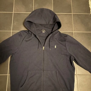 Ralph Lauren Hoodie  - En mycket fin & skön Hoodie från Ralph Lauren. Normal användning men som bibehållit ett gott skick. Storlek Large och nypris ligger på 2000kr. Tveka inte på att höra av dig vid minsta lilla fundering!