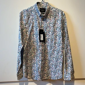 Blommig skjorta - Blommig skjorta från Bondelid i storlek M. Tailored fit. Ny, aldrig använd. Ordinarie pris 699 kr.