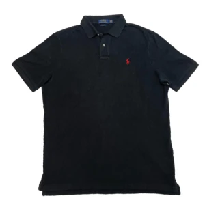 Svart Ralph Lauren piké  - En jättefin svart Ralph Lauren piké i storlek L den är i mycket fint skick förutom ett litet hål vid nacken som syns på bild fyra fråga gärna om extra bilder eller prisförslag👍