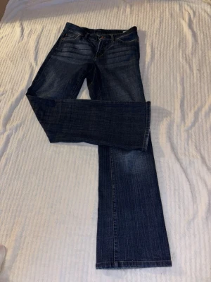 Bootcut jeans - Snygga blå bootcut jeans med klassisk femficksdesign. Jeansen har broderad logga på bakfickan och är tillverkade i denim med en skön passform. Innerbenslängd: 83 cm, midjemått: 41 cm rakt över 