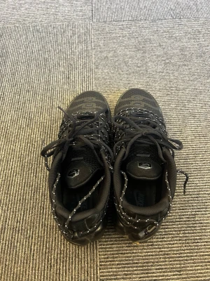 Svarta Nike sneakers med mönster - Snygga svarta Nike sneakers med diskret mönster på ovandelen och svarta skosnören med vita detaljer. Skorna har en sportig look med meshmaterial för bra andningsförmåga och en låg siluett som passar till streetwear. Perfekta för dig som gillar stilrena och bekväma sneakers.