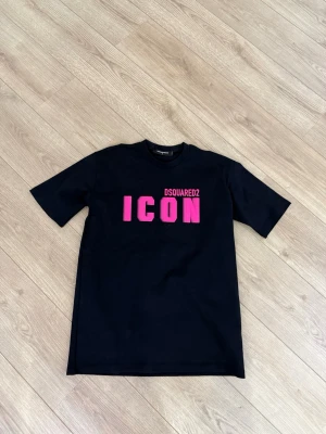 Svart DSQUARED2 ICON t-shirt -  Svart t-shirt från DSQUARED2 med stor rosa 'ICON'-text på bröstet. Modellen är over-size så den kommer se lite extra hängig ut.