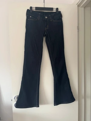 Mörkblå bootcut jeans Cheap Monday - Snygga mörkblå bootcut jeans från Cheap Monday med rosa detalj där bak men tyvärr är dem förstora i midjan på mig. Dem är helt nya med ingen prislapp ( storlek 27/30 )