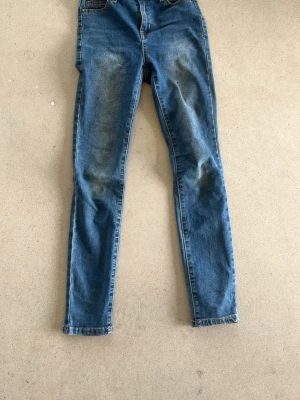 Blå skinny jeans med slitningar - Snygga blå skinny jeans med lätt slitna detaljer på framsidan och baksidan. Klassisk femficksmodell med normal midja och smal passform. Perfekta för en avslappnad och trendig look.