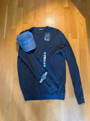 Mörkblå tröja från Dressmann - Helt ny, snygg mörkblå tröja från Dressmann i mjuk Supima-bomull. Tröjan har rund halsringning och långa ärmar, perfekt för en stilren och enkel look. Passar till jeans eller chinos för en clean outfit.