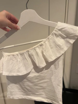 Vit offshoulder topp med volang - Snygg vit offshoulder topp med volangdetalj längs överkanten. det är storlek 152 men passar mig som har xs/xxs.