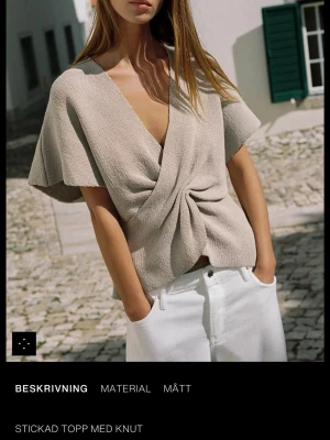 Beige stickad omlottopp med knut - Trendig beige stickad topp med omlott-design och knut framtill. Toppen har korta, vida ärmar och djup v-ringning. Perfekt för en avslappnad men stilren look. Köpte den och har aldrig använt den, lappen sitter kvar och tänkte sälja för originalpris. 