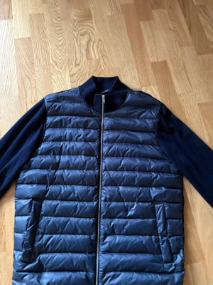 Mörkblå stickad jacka Massimo Dutti - Snygg mörkblå stickad jacka från Massimo Dutti med quiltad framsida och ärmar i mjukt stickat material. Jackan har dragkedja framtill och två fickor. Perfekt för lager-på-lager och stilrena outfits.