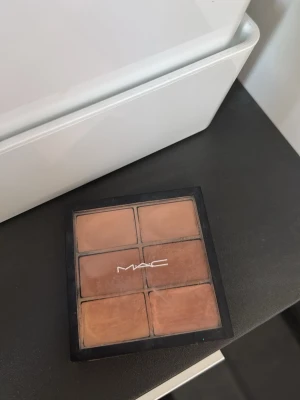MAC foundationpalett med 6 nyanser - Säljer en foundationpalett från MAC med sex olika nyanser i varma och neutrala toner. Paletten har en fyrkantig form och är perfekt för att blanda fram rätt färg till din hudton. Kommer i en svart plastförpackning med genomskinligt lock och MAC-logga.