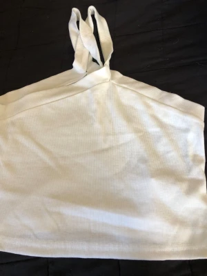 Vit ribbad oneshoulder topp - Snygg vit ribbad topp med oneshoulder-design och dubbla axelband på ena sidan. Perfekt för dig som gillar trendiga och stilrena plagg. Toppens material är stretchigt och bekvämt.