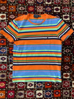 Unik randig Ralph Lauren T-Shirt - Säljer en otroligt snygg och unik T-shirt från Ralph Lauren som är i helt nytt skick. Tröjan säljs inte längre och är väldigt unik. Hör av dig vid frågor om pris osv!