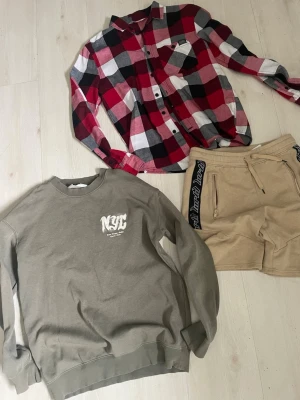 Beige shorts med svarta detaljer - Säljer ett par beige shorts från North Peak med svarta detaljer längs sidorna och dragkedjor på fickorna. Shortsens material är mjukt och känns som bomull eller syntet, perfekta för en avslappnad stil.