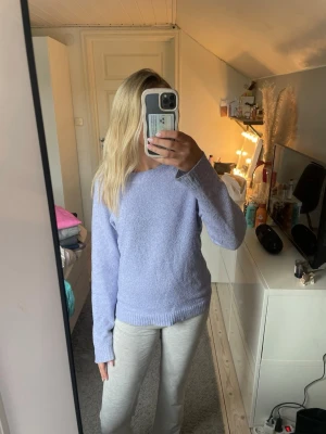 Ljuslila stickad tröja - Mysig ljuslila stickad tröja med rund halsringning och långa ärmar. Tröjan har en avslappnad passform och ribbade muddar och nederkant.