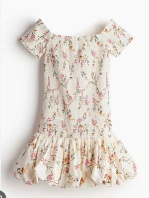 Blommig off shoulder klänning från hm - Söt kortklänning i ljus färg med blommigt mönster och volang nedtill. Klänningen har korta ärmar och offshoulder-design, perfekt för varma dagar. Väldigt stretchigt material så passar även till någon som har S. Knappt använd och därför i väldigt bra skick. Kontakta för egna bilder