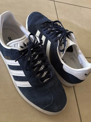Adidas Gazelle  - Snygga Adidas Gazelle sneakers i mörkblå mocka med vita detaljer. Använda ett fåtal gånger. Hör av er vid funderingar🙏🏽