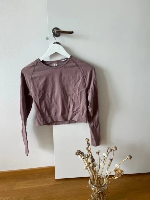 Ljuslila croppad långärmad topp 157 - Trendig ljuslila croppad långärmad topp från 157. Tillverkad i mjuk bomull med rund halsringning och enkel design. Perfekt att styla med jeans eller kjol för en avslappnad look.