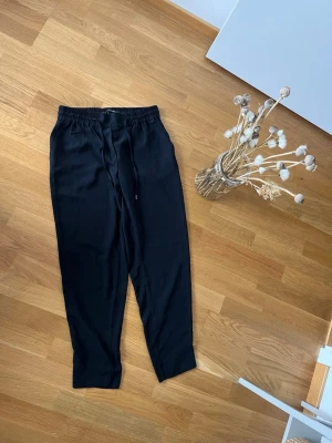 Svarta mjukisbyxor First Class S - Svarta mjukisbyxor från First Class Collection med avslappnad passform och resår i midjan samt dragsko. Tillverkade i ett mjukt och följsamt material som känns skönt mot huden. Perfekta för chill dagar eller när du vill ha det bekvämt.