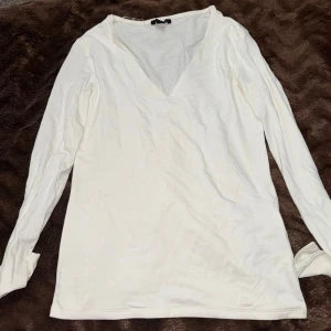 Vit långärmad topp från New yorker  - Snygg vit långärmad topp från New yorker  med v-ringning. Enkel och stilren design som passar till många olika outfits. Tillverkad i ett mjukt och bekvämt material som känns skönt mot huden.