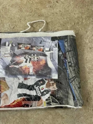 Juventus påslakanset med fotbollstryck - Säljer ett Juventus påslakanset med stort fotbollsmotiv och klubbens logga. Setet har svartvita färger med inslag av orange och rött, samt tryck av spelare och Jeep-loggan. Perfekt för dig som älskar fotboll och vill ha ett sportigt tema i sovrummet.