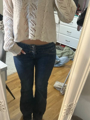 Mörkblå bootcut jeans med hög midja - Snygga mörkblå bootcut jeans med hög midja och fyra knappar framtill. 