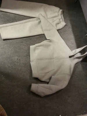 Scuba grey tracksuit - Säljer ett par beiga mjukisbyxor med avslappnad passform och resår i midjan. Tillverkade i mjukt och skönt material, perfekta för chill dagar. Matcha med hoodie för en komplett look.