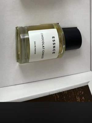ESSNCE Chocolat Chaud parfym - ESSNCE Chocolat Chaud Eau de Parfum i en stilren, rund glasflaska med svart lock.  Perfekt för dig som gillar unika och varma dofter med chokladtoner.