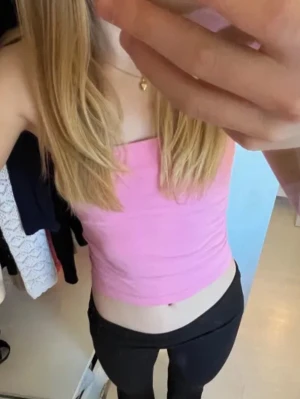 Rosa tubtop - Säljer en söt rosa tubtop i stretchigt material. Toppen är ärmlös och har en kroppsnära passform, perfekt för att skapa en trendig och avslappnad look. Enkel design utan tryck eller detaljer.