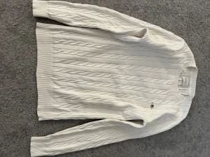 Vit kabelstickad tröja Gant - Kabelstickad vit tröja från Gant med rund halsringning och diskret logga broderad på bröstet. Tröjan är kräm vit med en vanlig gant logga. Den är sparsamt använd och i fint skick. De är bara att höra av sig om man vill ha fler bilder eller har frågor.