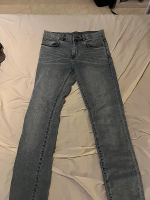 Blå slim fit jeans - Säljer ett par klassiska blå slim fit jeans köpta från Jack & Jones med fem fickor och normal midja. Jeansen har en snygg tvättad look och raka ben. Perfekta för en avslappnad stil och passar till det mesta. Materialet är mjukt denim som ger en skön känsla hela dagen. 