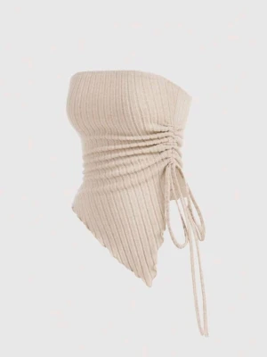 Beige ribbad tubtopp med snörning - Trendig beige tubtopp i ribbat material med snörningsdetalj på sidan. Toppen har asymmetrisk nederkant och är axelbandslös, perfekt för en cool och modern look. Passar dig som gillar stilrena och unika plagg.
