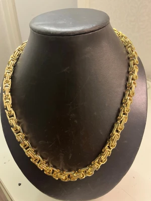 Tjockt guldfärgat kedjehalsband - Säljer ett maffigt halsband i guldfärg med kraftiga, rektangulära länkar som ger ett riktigt statement-utseende. Halsbandet har en glänsande finish och känns både trendigt och klassiskt. Perfekt för dig som vill sticka ut med accessoarerna.