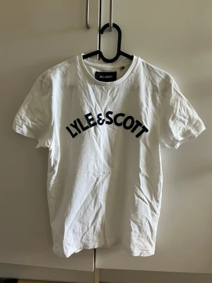 Vit Lyle & Scott t-shirt med tryck - Vit t-shirt från Lyle & Scott med marinblått tryck.