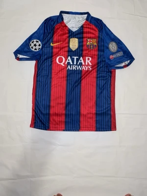 Barcelona matchtröja blå/röd storlek M - Säljer en FC Barcelona matchtröja i blått och rött med vertikala ränder. Tröjan har klubbmärke, Nike-logga och Qatar Airways som sponsor framtill samt Champions League- och Respect-märken på ärmarna. Perfekt för dig som älskar fotboll och vill stötta Barca!
