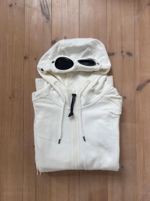 Vit hoodie med glasögon från C.P. Company - Säljer en kritvit hoodie från C.P. Company i storlek M. Inga konstigheter, du får varmt höra av dig vid frågor! 