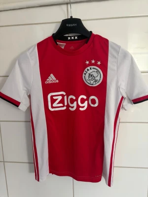 Ajax fotbollströja röd/vit Adidas - Ajax tröja från året där de tog sig till semifinal i CL. Har även en av deras nyckelspelare De Ligt på ryggen. Storlek är 13-14 åringar