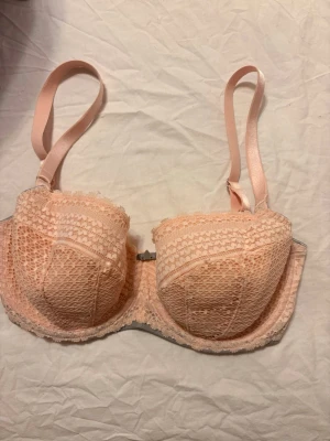 Ljusrosa spets-bh från Freya - Söt ljusrosa bh från Freya med vadderade kupor och vacker spetsdetalj över hela framsidan. Bh:n har justerbara axelband och hakknäppning bak. Materialet är en mix av polyamid och elastan för skön stretch och passform.