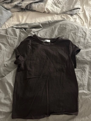 Brun basic t-shirt i bomull - En enkel brun t-shirt i mjuk bomull med rund hals och korta ärmar. Perfekt att matcha med jeans eller shorts för en clean och avslappnad look. Klassisk passform och tidlös stil.