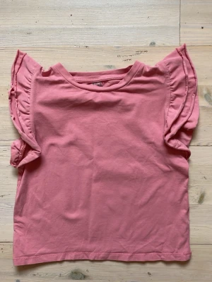 Rosa topp - Rosa topp/linne/blus med volanger på axlarna från Lager157. I storlek M men det är en liten passform, jag som brukar ha xs/s hade den i storlek m då jag inte ville att att den skulle sitta helt tajt. Säljs inte längre.