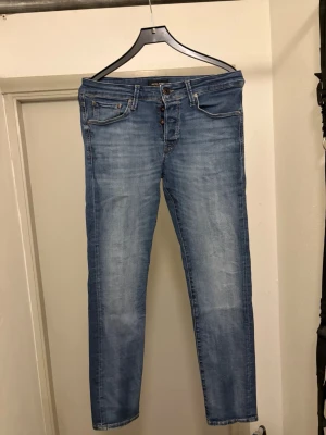 Jack&Jones jeans - Säljer ett par ljusblå slim fit jeans med klassisk femficksdesign och knappgylf. Jeansen har en snygg tvättad look och raka ben. Perfekta för dig som gillar en enkel och stilren stil. Modellen heter slim glen. 699 nypris. Kan gå ner i pris vid en snabb affär!