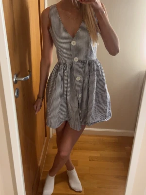 Randig sommarklänning med knappar - Kort, ärmlös klänning med smala blå och vita ränder och stora vita knappar framtill. Den är ifrån american apparel och är i storlek S! Pris kan diskuteras 🩷