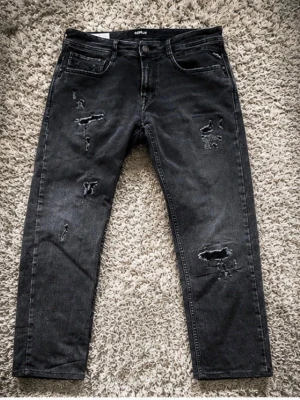 Replay jeans med slitningar  - Säljer ett par svarta jeans med trendiga slitningar och hål på framsidan. 39 cm i midjan och 91cm på längden. Inga defekter. Hör av er vid minsta lilla fråga //Wallsten