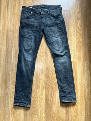 Svarta slim fit jeans från Jack & Jones - Snygga svarta slim fit jeans från Jack & Jones med klassisk femficksmodell och diskret tvättad look. Jeansen har dragkedjegylf och detaljer i metall. Perfekta till en avslappnad streetstil.