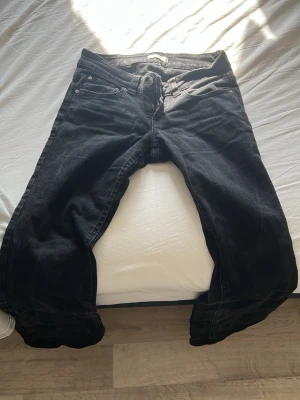Svarta raka jeans med fem fickor - Säljer ett par svarta jeans med klassisk femficksmodell och raka ben. Jeansen har normal midja och är tillverkade i ett slitstarkt denimtyg. Perfekta för dig som gillar en enkel och tidlös stil.
