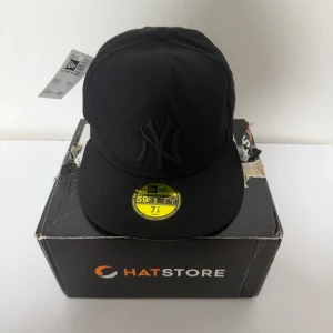 New Era NY 59Fifty Cap – Size 7 1/8 (56,8cm) - Kepsen är helt ny, inga skador eller slitage och tagsen sitter kvar.  Klassisk New Era 59FIFTY fitted-keps med den ikoniska NY-loggan i svart. Stilren design som passar perfekt till alla outfits.  Storlek: 7 1/8 (56,8cm) Rabatt vid köp av flera plagg!