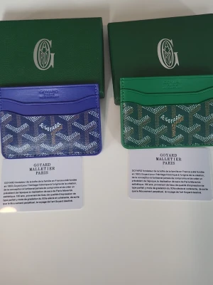Grön korthållare från G0Y4RD - Snygg grön korthållare från G0Y4RD med det klassiska mönstret och texten 'G0Y4RD Honore Paris' på framsidan. Tillverkad i exklusivt läder med flera fack för kort. Perfekt accessoar för dig som vill ha något unikt och stilrent.